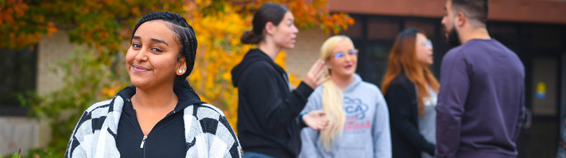 La Roche students outside in front of library socializing with fall foliage in background