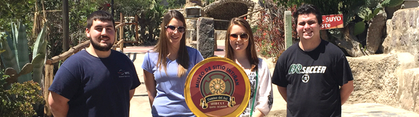 Four La Roche University students posing near a sign in a sunny outdoor setting during a study abroad trip.