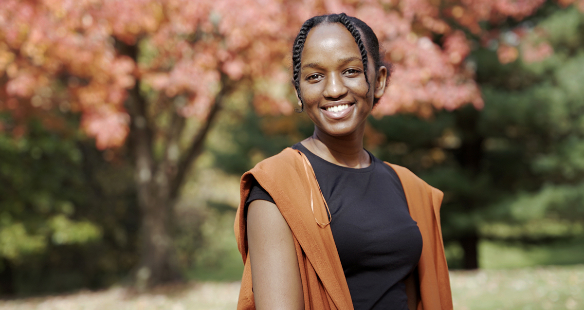 A La Roche University student smiling in an outdoor setting with autumn trees in the background.