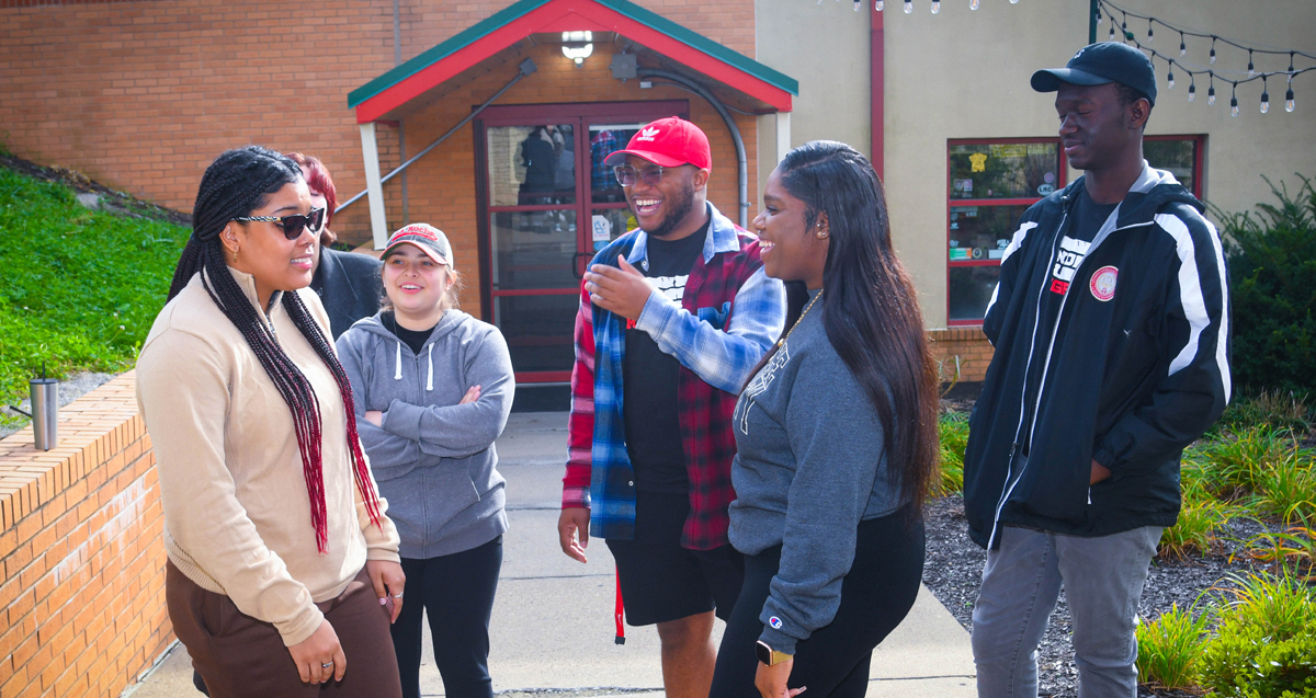 Group of five La Roche University students chatting and smiling outside.