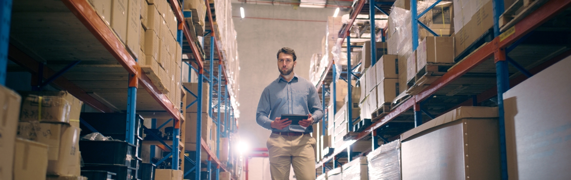 A person holding a clipboard walks through a warehouse. 
