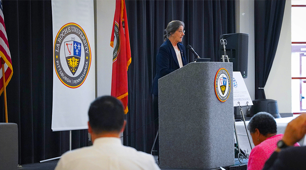 Dr. Patricia M. DeMarco stands in front of a podium to deliver a keynote address at a La Roche University conference. 