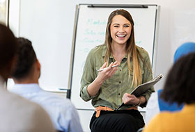 Female grauate student speaking in front of a class.