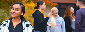 LRU students gathered in front of the library socializing with fall foliage in background