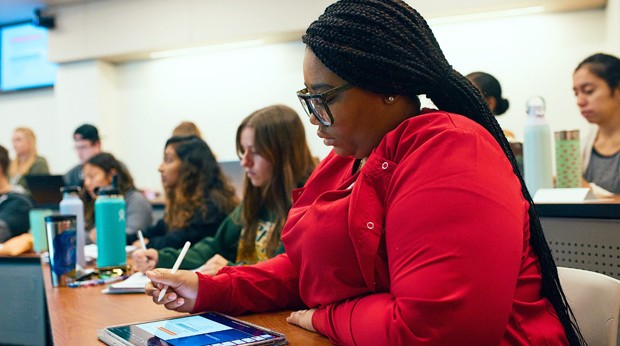 La Roche University students taking notes while attending a lecture in a classroom.