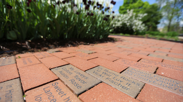 A close up of commemorative bricks surrounded by flowers on the La Roche University campus.