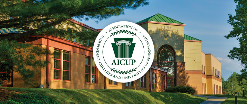 Exterior view of La Roche University's Zappala Campus Center Square building under a clear sky, featuring lush greenery and the logo of the Association of Independent Colleges and Universities of Pennsylvania (AICUP).