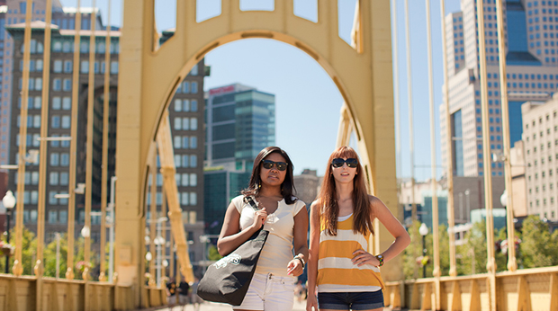 Two female students standing on bridge in downtown Pittsburgh