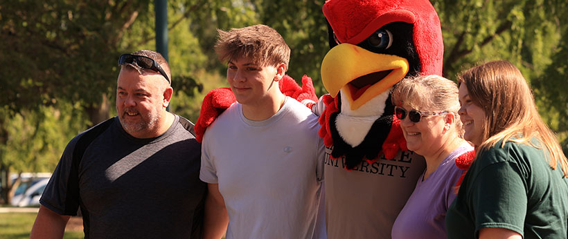 New student posing with the Redhawk and their family