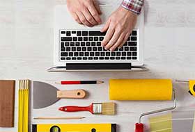 Hands typing at at laptop keyboard with tools for design on table near laptop