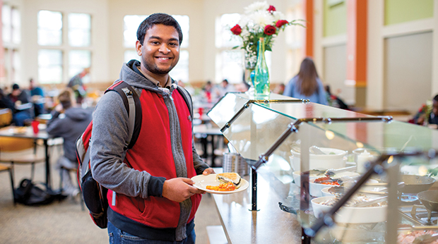 A La Roche University student stands with a plate of food near a buffet station in the Cantellops Dining Hall.