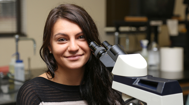 A La Roche University student sits behind a microscope.
