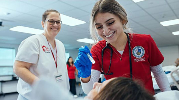 A La Roche University nursing student assesses a mannequin in the clinical simulation center. A faculty member stands beside her.