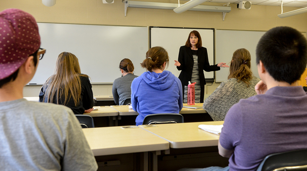 A La Roche University professors stands in front of students in a classroom. A white board is behind the professor.