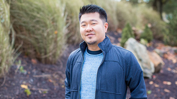 A La Roche University stands outside. Tall grasses are behind him.