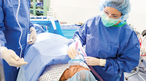 An anesthesiologist preparing a patient for surgery in an operation room.