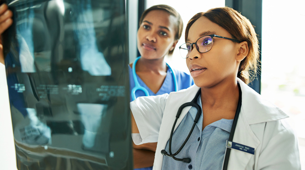 Two medical professionals examining an X-ray film together in a well-lit room.
