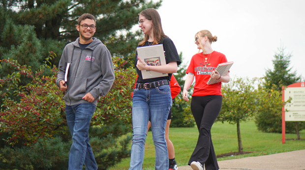3 students walking on campus with books at LRU campus.